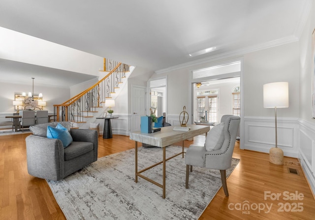 living room featuring stairs, crown molding, visible vents, and light wood-style floors