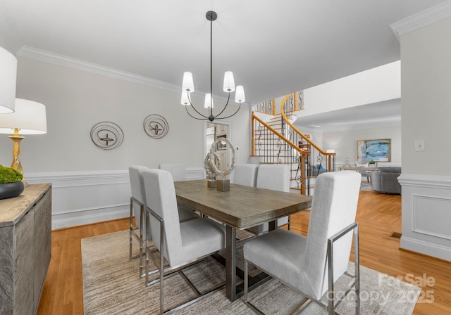 dining room with wainscoting, stairs, a chandelier, and ornamental molding