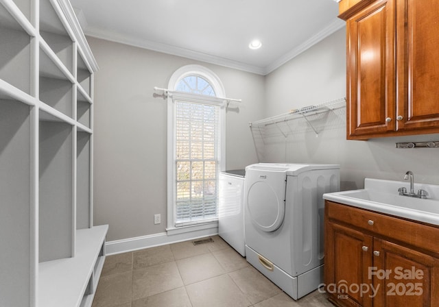 laundry area with a sink, washing machine and clothes dryer, cabinet space, and crown molding