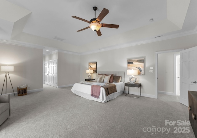 bedroom with ornamental molding, a tray ceiling, light carpet, and baseboards