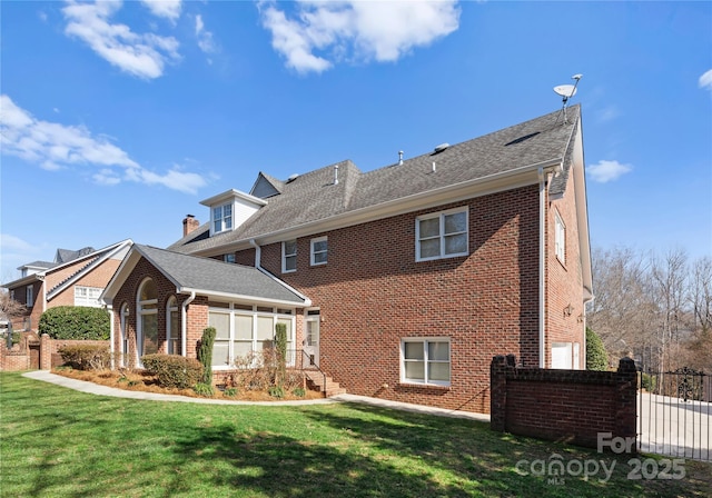 back of property featuring a yard, brick siding, and fence