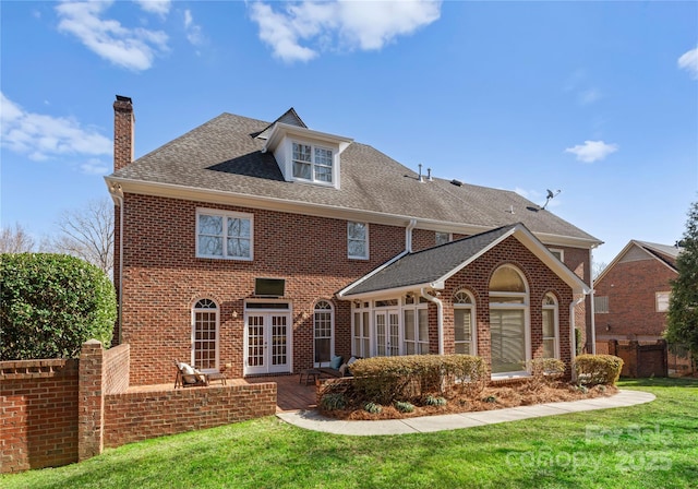 rear view of house featuring a yard, french doors, and brick siding