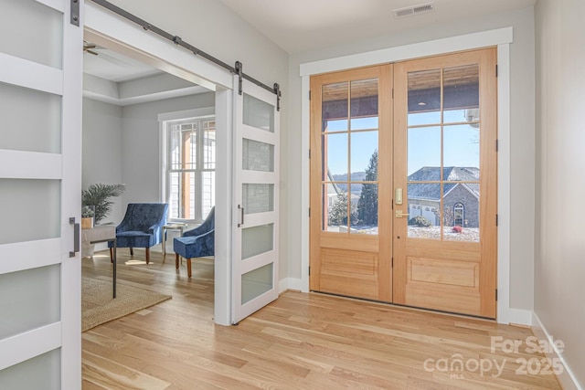 entryway featuring a barn door, hardwood / wood-style floors, and french doors