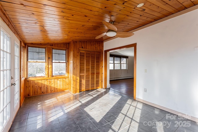 tiled spare room with a baseboard heating unit, wood ceiling, wooden walls, and ceiling fan