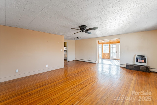 unfurnished living room with hardwood / wood-style floors, ceiling fan, heating unit, and baseboard heating