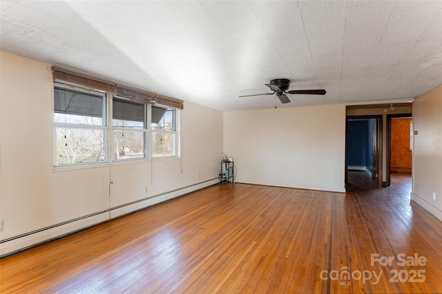 empty room featuring wood-type flooring, ceiling fan, and baseboard heating