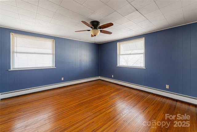 spare room featuring a baseboard heating unit, wood-type flooring, and ceiling fan