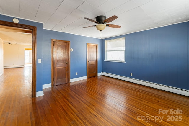 unfurnished bedroom featuring multiple windows, hardwood / wood-style flooring, and baseboard heating