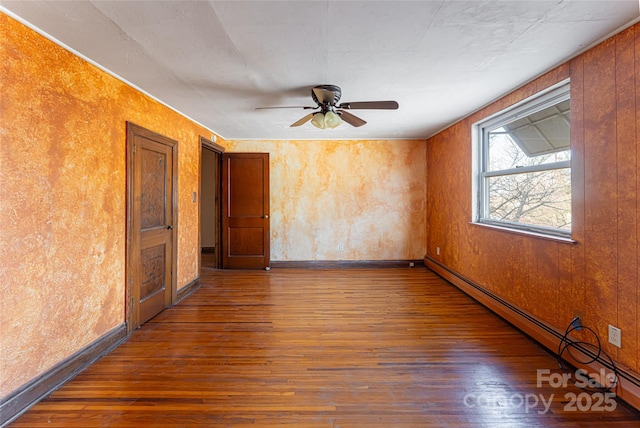 unfurnished room featuring a baseboard heating unit, dark wood-type flooring, and ceiling fan