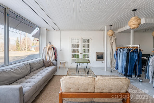 living room featuring heating unit, plenty of natural light, concrete flooring, and french doors