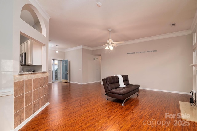 living area with crown molding, dark hardwood / wood-style floors, and ceiling fan