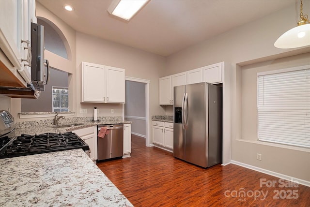 kitchen with white cabinetry, appliances with stainless steel finishes, dark hardwood / wood-style flooring, and hanging light fixtures