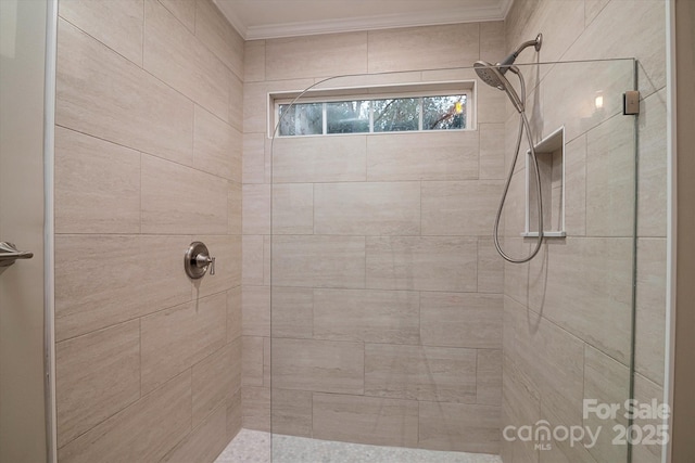 bathroom with ornamental molding and tiled shower