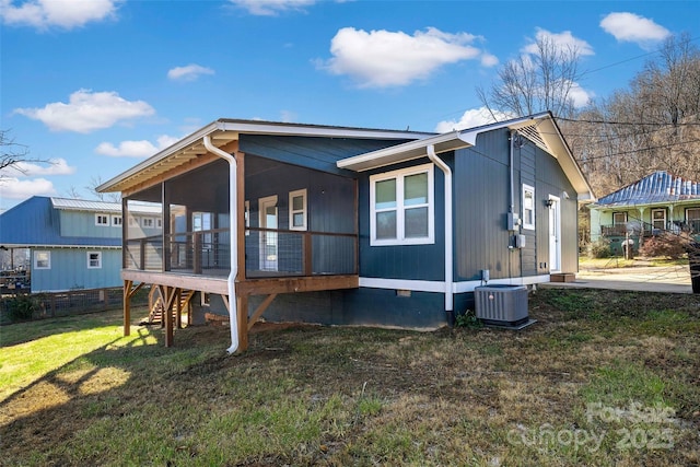 back of property with cooling unit, a yard, and a sunroom