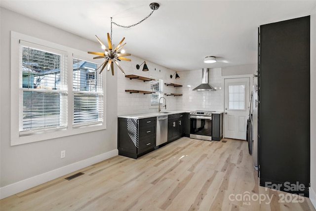 kitchen featuring wall chimney range hood, decorative backsplash, stainless steel appliances, and a healthy amount of sunlight