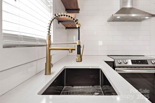 details with tasteful backsplash, electric range, sink, and exhaust hood