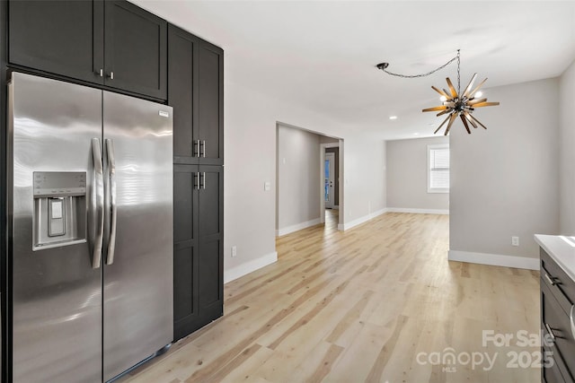 kitchen with stainless steel fridge, light hardwood / wood-style floors, and a notable chandelier