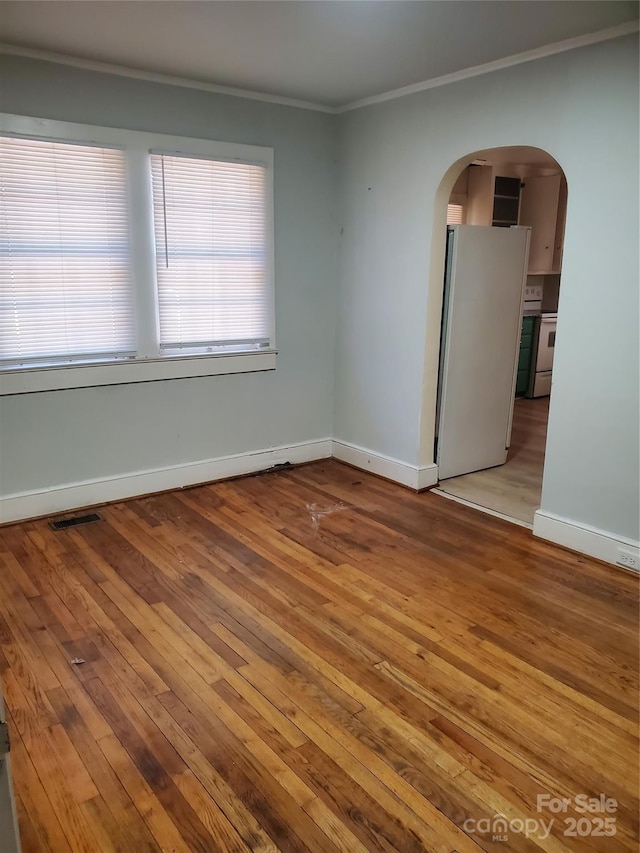 spare room with crown molding, a healthy amount of sunlight, and wood-type flooring