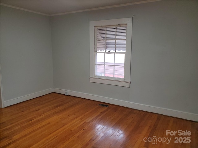 spare room featuring hardwood / wood-style floors and ornamental molding