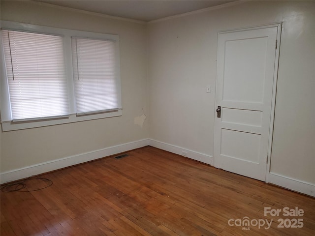 empty room with hardwood / wood-style flooring and ornamental molding