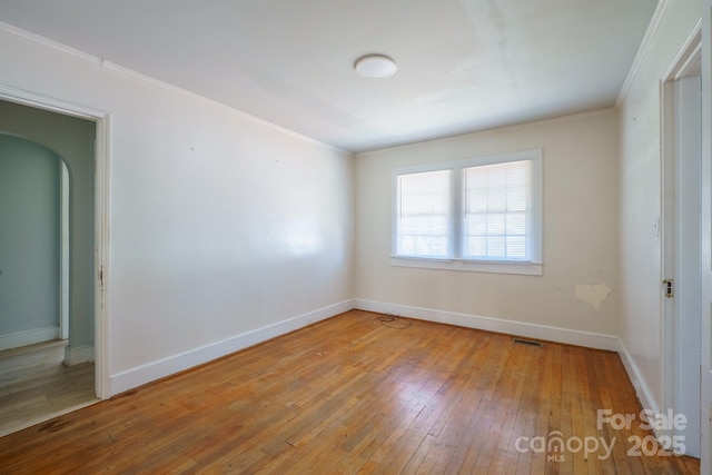 empty room with ornamental molding and hardwood / wood-style floors