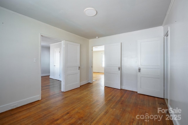 unfurnished bedroom featuring ornamental molding and dark wood-type flooring