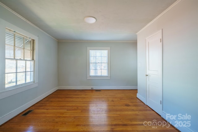 empty room with ornamental molding, a healthy amount of sunlight, and hardwood / wood-style floors