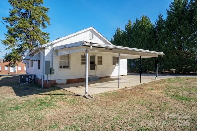 rear view of property featuring a carport, central AC unit, and a lawn