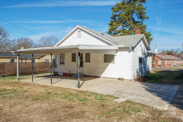 rear view of property featuring a yard and a carport