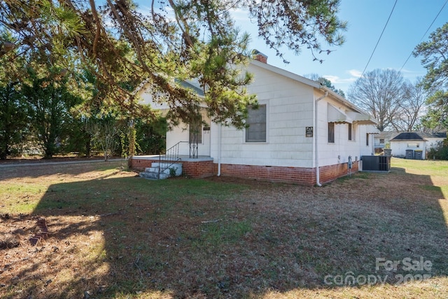 view of side of home with central AC unit and a yard