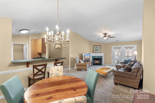 dining room featuring light carpet, ceiling fan with notable chandelier, and vaulted ceiling