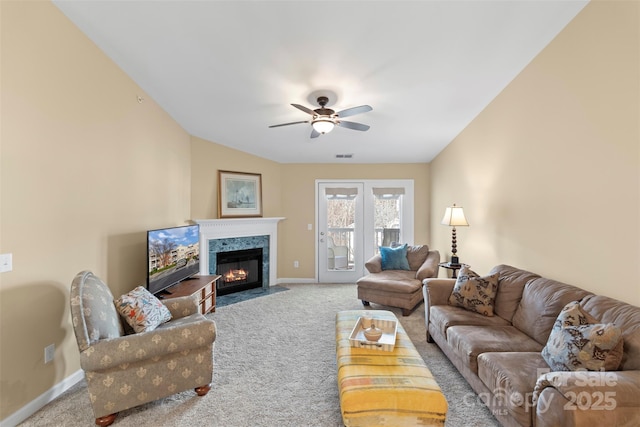 carpeted living room with a high end fireplace and ceiling fan