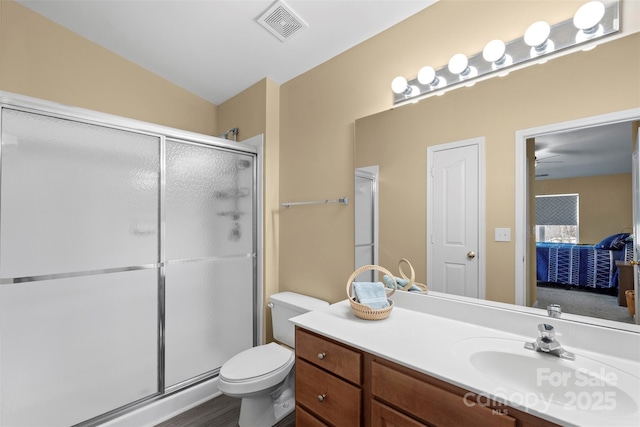 bathroom featuring vanity, vaulted ceiling, a shower with door, and toilet