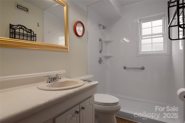 bathroom with vanity, a shower, and toilet