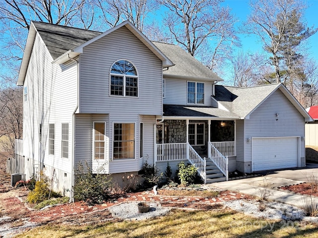 view of front of home with cooling unit, a garage, and covered porch