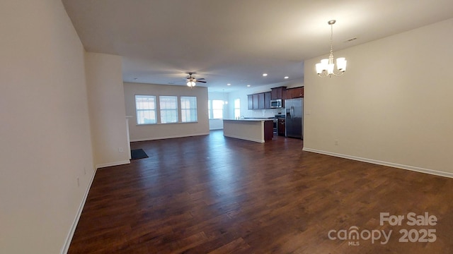 unfurnished living room featuring ceiling fan with notable chandelier and dark hardwood / wood-style floors