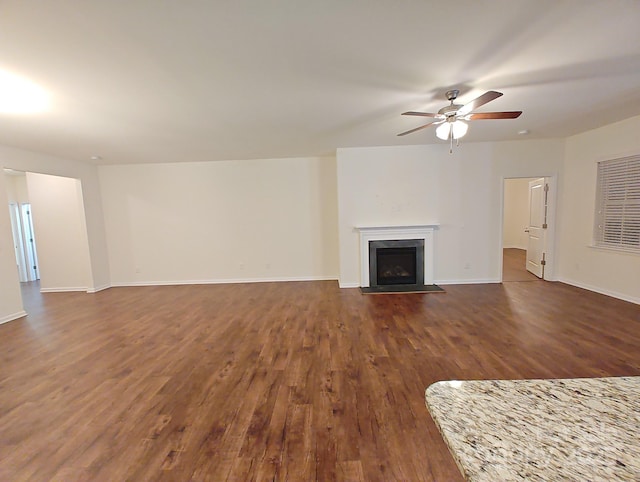 unfurnished living room featuring dark wood-type flooring and ceiling fan