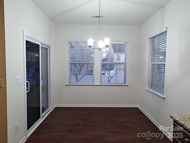 unfurnished dining area featuring an inviting chandelier and dark hardwood / wood-style floors