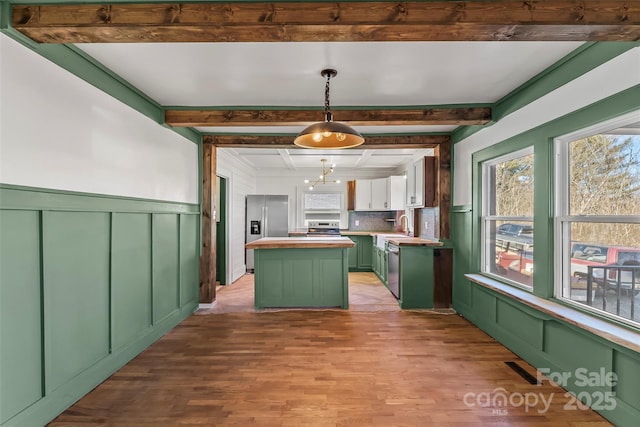 kitchen featuring beam ceiling, decorative light fixtures, a center island, and green cabinetry