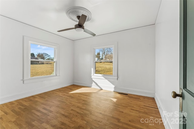 unfurnished room featuring ceiling fan, plenty of natural light, and wood-type flooring