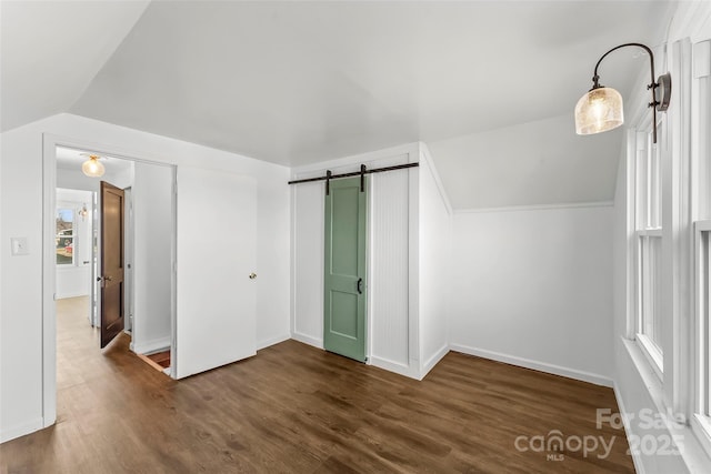 bonus room featuring a barn door, dark hardwood / wood-style floors, and lofted ceiling