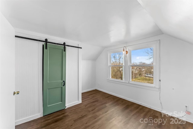 bonus room with vaulted ceiling, dark hardwood / wood-style floors, and a barn door