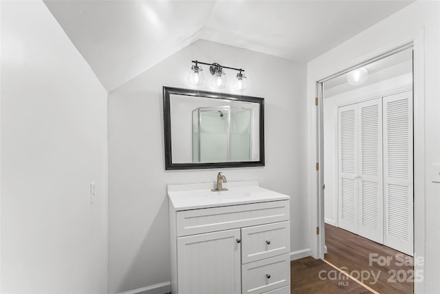 bathroom with vanity, hardwood / wood-style flooring, and vaulted ceiling