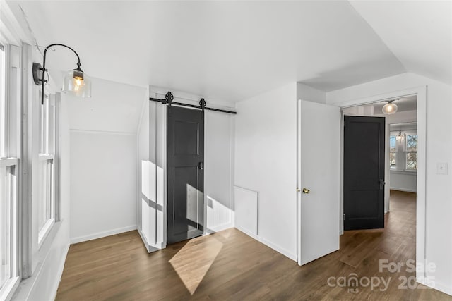 interior space featuring vaulted ceiling, a barn door, and dark wood-type flooring