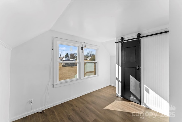 additional living space with lofted ceiling, wood-type flooring, and a barn door