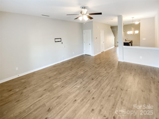 empty room with wood-type flooring and ceiling fan with notable chandelier