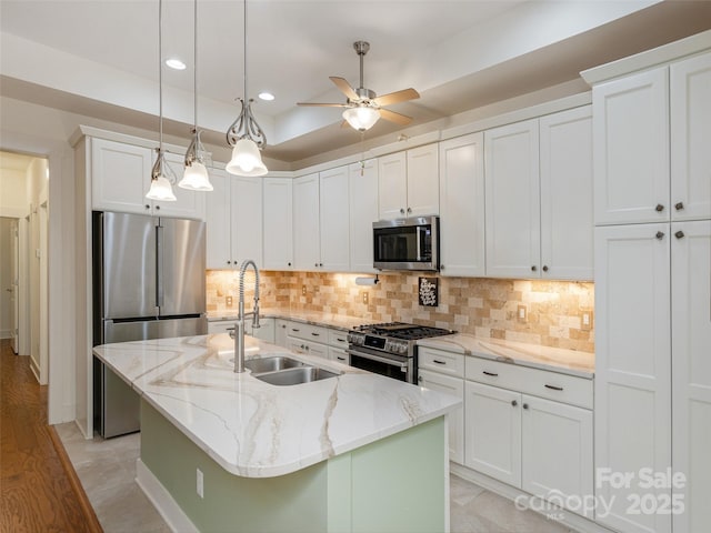 kitchen with white cabinetry, sink, stainless steel appliances, and an island with sink