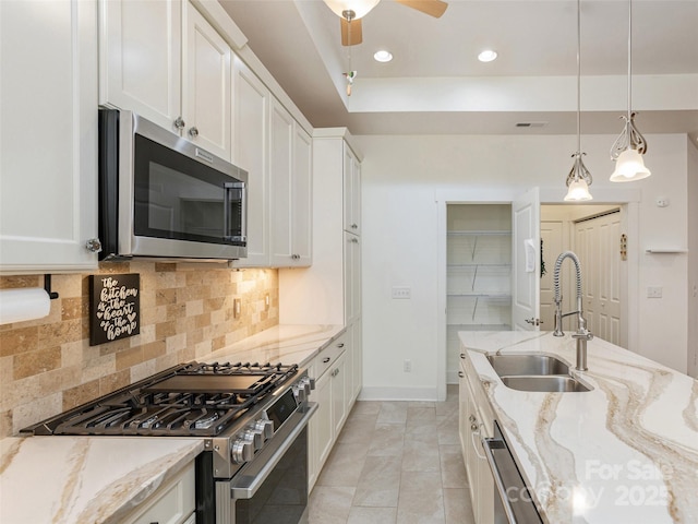 kitchen with light stone counters, stainless steel appliances, sink, and white cabinets