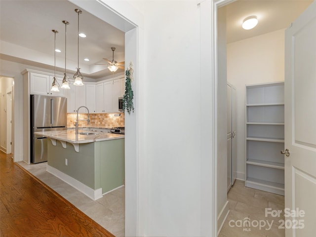 kitchen with sink, a breakfast bar area, appliances with stainless steel finishes, white cabinetry, and hanging light fixtures