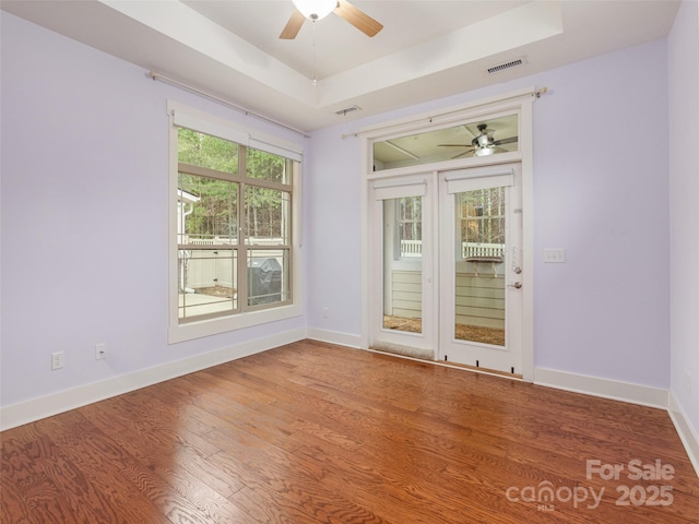 empty room featuring hardwood / wood-style floors, a tray ceiling, and ceiling fan